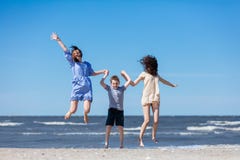 Famiglia felice che salta su sulla spiaggia fotografia stock Famiglia felice che salta su sulla spiaggia fotografia stock
