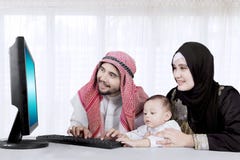 Famiglia musulmana facendo uso del computer online a casa immagini stock libere da diritti Famiglia musulmana facendo uso del computer online a casa immagini stock libere da diritti