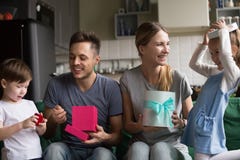 Famiglia numerosa felice che disimballa i regali con il figlio e la figlia fotografia stock Famiglia numerosa felice che disimballa i regali con il figlio e la figlia fotografia stock