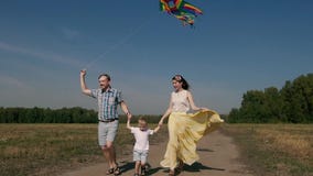 Familia alegre que vuela una cometa y un funcionamiento en el camino con él metrajes Familia alegre que vuela una cometa y un funcionamiento en el camino con él metrajes