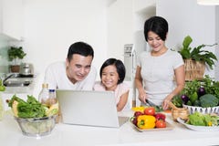 Familia asiática joven usando el ordenador junto en casa imagen de archivo Familia asiática joven usando el ordenador junto en casa imagen de archivo