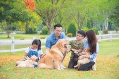 Familia con los perros que se sientan en el parque foto de archivo Familia con los perros que se sientan en el parque foto de archivo