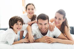 Familia de cuatro miembros que miente en cama imagen de archivo libre de regalías Familia de cuatro miembros que miente en cama imagen de archivo libre de regalías
