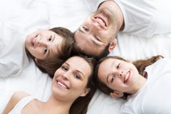 Familia de cuatro miembros que miente en cama fotos de archivo Familia de cuatro miembros que miente en cama fotos de archivo