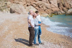 Familia de padre de abuelo y de hijo en una playa rocosa el vacaciones que disfrutan del tiempo junto imagen de archivo Familia de padre de abuelo y de hijo en una playa rocosa el vacaciones que disfrutan del tiempo junto imagen de archivo