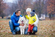 Familia feliz que juega con un perro del samoyedo en parque del otoño fotos de archivo libres de regalías Familia feliz que juega con un perro del samoyedo en parque del otoño fotos de archivo libres de regalías