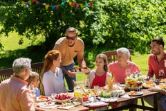 Familia feliz que tiene la cena o la fiesta de jardín del verano foto de archivo libre de regalías Familia feliz que tiene la cena o la fiesta de jardín del verano foto de archivo libre de regalías