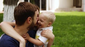 Familia feliz, sonriente La madre, padre, pequeño hijo se está abrazando Madre que besa el niño pequeño y a su marido almacen de video Familia feliz, sonriente La madre, padre, pequeño hijo se está abrazando Madre que besa el niño pequeño y a su marido almacen de video