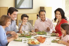 Familia hispánica extendida que disfruta de la comida en casa imagen de archivo Familia hispánica extendida que disfruta de la comida en casa imagen de archivo