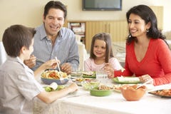 Familia hispánica joven que disfruta de la comida en casa imagenes de archivo Familia hispánica joven que disfruta de la comida en casa imagenes de archivo