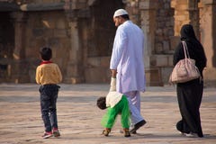 Familia india que camina a través del patio del mosqu del Quwwat-UL-Islam foto de archivo Familia india que camina a través del patio del mosqu del Quwwat-UL-Islam foto de archivo