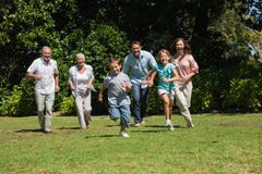 Familia multi feliz de la generación que corre hacia cámara imagen de archivo libre de regalías Familia multi feliz de la generación que corre hacia cámara imagen de archivo libre de regalías