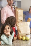 Familia que desempaqueta compras en cocina imagen de archivo Familia que desempaqueta compras en cocina imagen de archivo