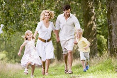 Familia que se ejecuta en la sonrisa de las manos de la explotación agrícola del camino imagen de archivo Familia que se ejecuta en la sonrisa de las manos de la explotación agrícola del camino imagen de archivo