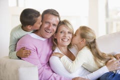 Familia que se sienta en la sala de estar que se besa y que sonríe Familia que se sienta en la sala de estar que se besa y que sonríe