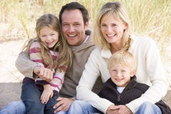 Familia que se sienta en la sonrisa de la playa imágenes de archivo libres de regalías Familia que se sienta en la sonrisa de la playa imágenes de archivo libres de regalías