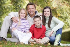 Familia que se sienta entre árboles del otoño Familia que se sienta entre árboles del otoño