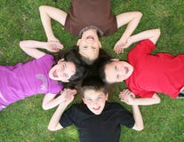 Familie der Geschwister, die auf dem Gras-Lachen liegen lizenzfreie stockfotos Familie der Geschwister, die auf dem Gras-Lachen liegen lizenzfreie stockfotos