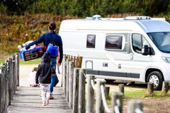 Familie die aan kampeerautobestelwagen lopen met doos van speelgoed royalty-vrije stock afbeelding Familie die aan kampeerautobestelwagen lopen met doos van speelgoed royalty-vrije stock afbeelding