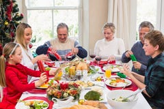 Familie die Kerstmiscrackers trekken bij de dinerlijst royalty-vrije stock foto Familie die Kerstmiscrackers trekken bij de dinerlijst royalty-vrije stock foto