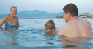 Familie, die mit Spielzeugfrosch im Meer spielt stock footage Familie, die mit Spielzeugfrosch im Meer spielt stock footage