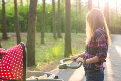 Familie, Kind und Elternschaftskonzept - junge Mutter, die einen Spaziergänger im Park mit neugeborenem geht und drückt Schön lizenzfreies stockbild Familie, Kind und Elternschaftskonzept - junge Mutter, die einen Spaziergänger im Park mit neugeborenem geht und drückt Schön lizenzfreies stockbild