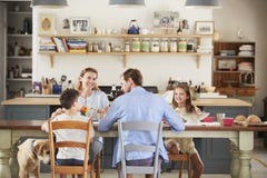 Familie met hond die samen bij de lijst in keuken eten stock afbeelding Familie met hond die samen bij de lijst in keuken eten stock afbeelding