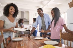 Familie mit den jugendlichen Töchtern, die Tabelle für Mahlzeit in der Küche legen stockfotografie Familie mit den jugendlichen Töchtern, die Tabelle für Mahlzeit in der Küche legen stockfotografie