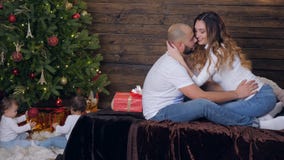 Familienidylle, verbinden leicht Küsse auf Bett am Vorabend des neuen Jahres auf den Hintergrundkindern, die unter Weihnachtsbaum stock video Familienidylle, verbinden leicht Küsse auf Bett am Vorabend des neuen Jahres auf den Hintergrundkindern, die unter Weihnachtsbaum stock video