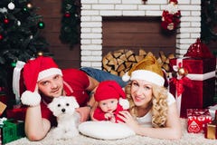Familj som ligger på golv nära spisen med den lilla sonen och hunden och ler på kameran royaltyfri fotografi Familj som ligger på golv nära spisen med den lilla sonen och hunden och ler på kameran royaltyfri fotografi