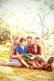 Familj som läser en bok i parkera royaltyfria foton Familj som läser en bok i parkera royaltyfria foton