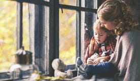 Familjmodern och barndottern ser ut fönstret på regnig höst royaltyfria bilder Familjmodern och barndottern ser ut fönstret på regnig höst royaltyfria bilder