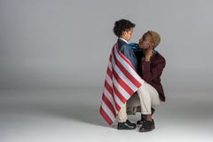 famille d'afro-américain enveloppée dans le drapeau sur le gris Image stock famille d'afro-américain enveloppée dans le drapeau sur le gris Image stock
