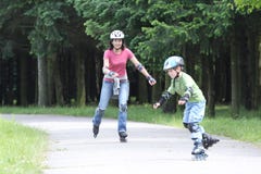 Famille heureuse apprenant à conduire sur des rollerblades photographie stock libre de droits Famille heureuse apprenant à conduire sur des rollerblades photographie stock libre de droits
