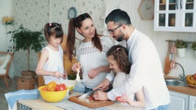 Famille heureuse préparant la nourriture sur la cuisine, coupant des légumes, mouvement lent banque de vidéos Famille heureuse préparant la nourriture sur la cuisine, coupant des légumes, mouvement lent banque de vidéos