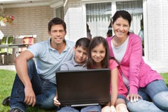 Famille heureux s'asseyant ainsi que l'ordinateur portatif Images stock Famille heureux s'asseyant ainsi que l'ordinateur portatif Images stock