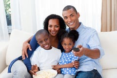 Famille mangeant du maïs éclaté et regardant la TV Famille mangeant du maïs éclaté et regardant la TV