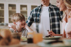 Famille positive souriant et semblant heureuse tout en ayant le repas images libres de droits Famille positive souriant et semblant heureuse tout en ayant le repas images libres de droits