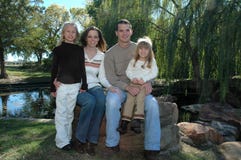 Family. An american family take their portraits in nature sitting outside on small waterfall. A family of four with two daughters and their parents Family. An american family take their portraits in nature sitting outside on small waterfall. A family of four with two daughters and their parents