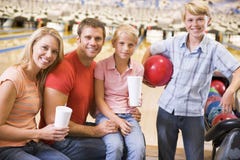 Family in bowling alley with drinks smiling