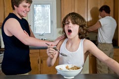 Family breakfast fun - teen brothers having cereal: candid shots stock photo Family breakfast fun - teen brothers having cereal: candid shots stock photo