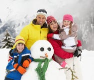 Family Building Snowman On Ski Holiday