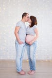 family concept - full length portrait of cute pregnant couple kissing over white brick wall stock photo family concept - full length portrait of cute pregnant couple kissing over white brick wall stock photo
