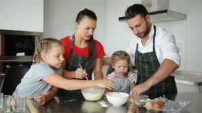 Family Cooking Together. They Have a Lot of Fun Playing On Kitchen. Cute Daughters With Their Handsome Parents Playing stock footage Family Cooking Together. They Have a Lot of Fun Playing On Kitchen. Cute Daughters With Their Handsome Parents Playing stock footage