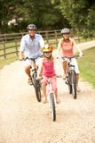 Family Cycling In Countryside Wearing Safety Helme