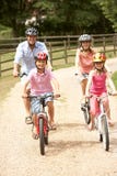 Family Cycling In Countryside Wearing Safety Helme