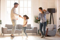 Family dancing in living room spending time on weekend together