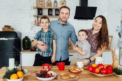 Family of four embracing sitting on the kitchen. Two sons hug their parents stock photography Family of four embracing sitting on the kitchen. Two sons hug their parents stock photography