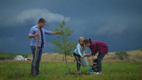 Family of four planting a new tree in his garden. The concept is to plant trees, a friendly family.