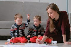 Family mom and two twin brothers draw together markers and felt pens sitting on the floor. royalty free stock photos Family mom and two twin brothers draw together markers and felt pens sitting on the floor. royalty free stock photos